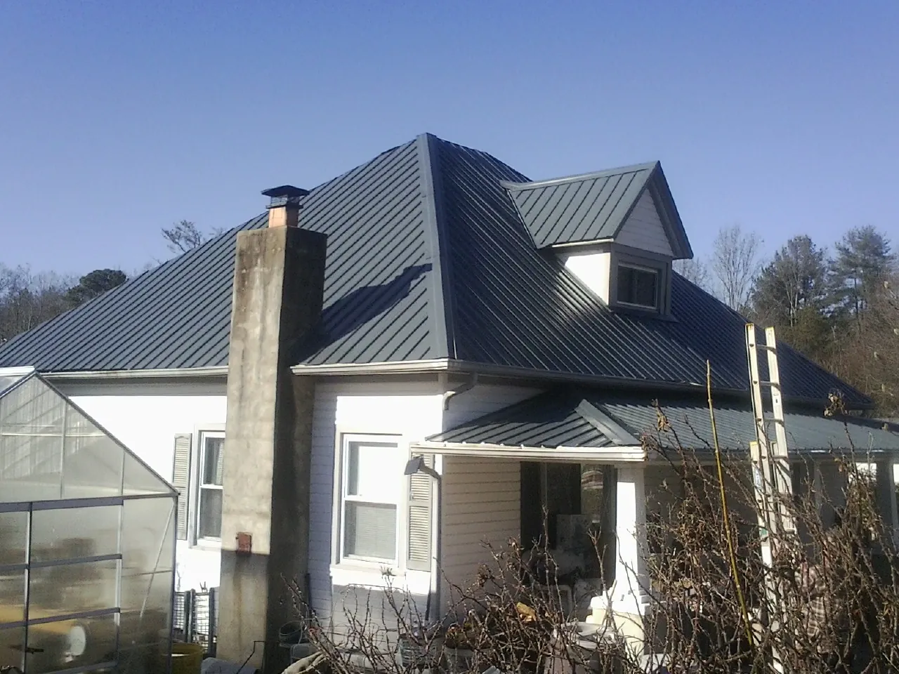 Dark blue standing seam metal roof on a white farmhouse with dormer — Slate & Tile Roof Repair by Roofing Brothers in Sassamansville