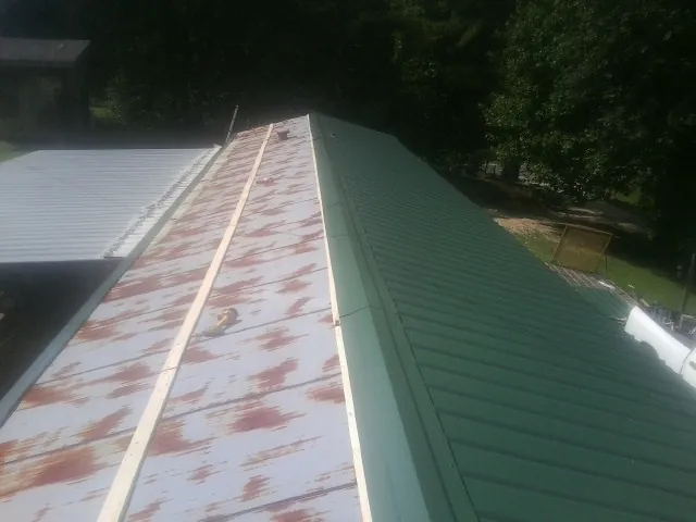 Old rusted panels beside newly installed green metal roofing — Wind Damage Roof Repair by Roofing Brothers in Sassamansville