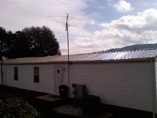 New metal roof on a single wide mobile home with a TV antenna in Sassamansville