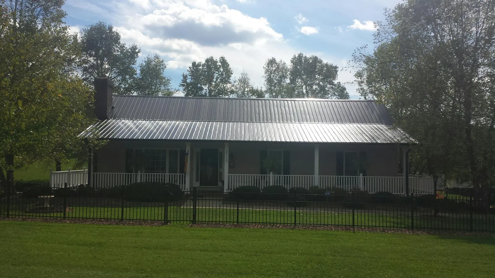 Gray metal roof on a brick ranch with a full width front porch — Gutter Guard Installation work by our crew in Sassamansville