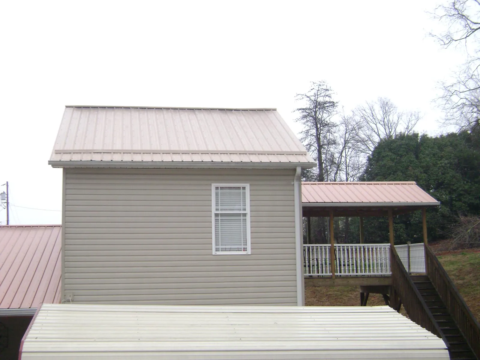 Tan metal roofs on a two story addition and attached porch, from a Roof Replacement job in Sassamansville