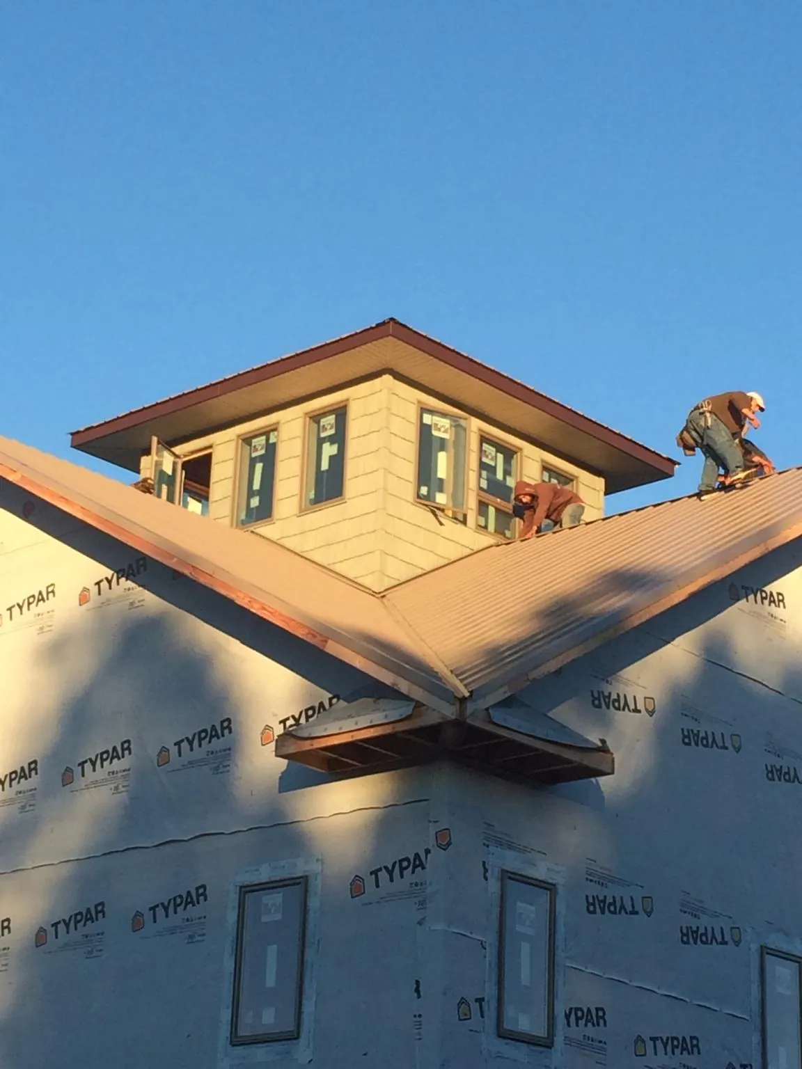 Roofers working around a rooftop cupola on a new metal roof at sunset — Roof Waterproofing in Sassamansville by Roofing Brothers